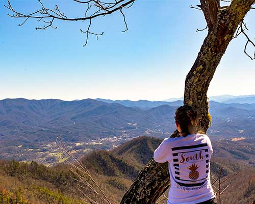 Woman leaning on a tree taking in the mountain views of Bryson City NC from Lonesome Pine Overlook